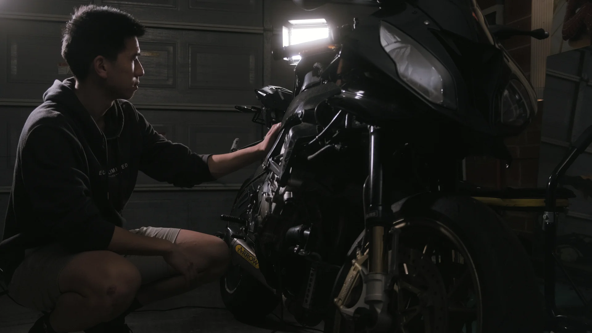 Eddy crouched beside a stripped superbike in a garage, one light panel on the bike